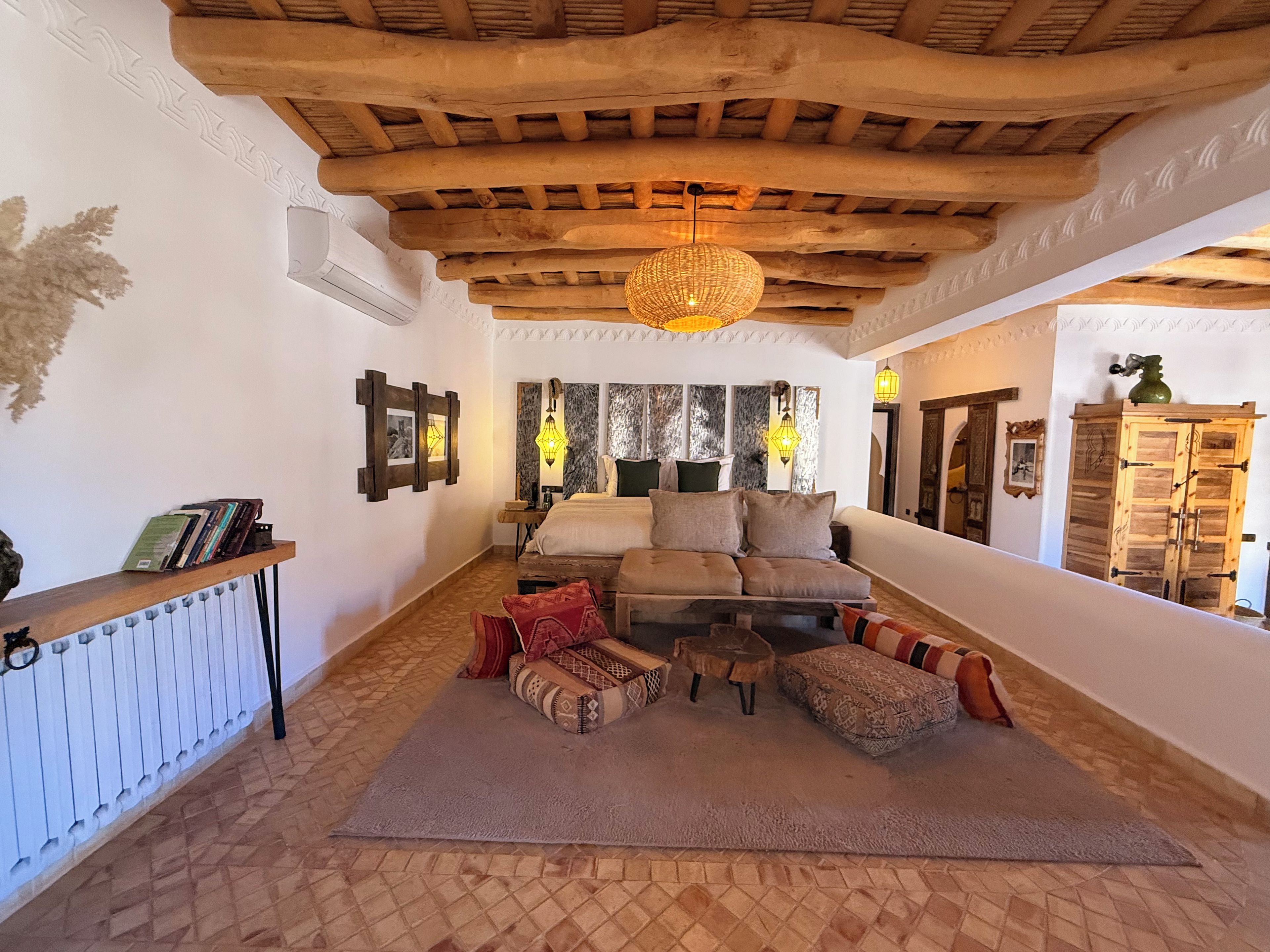 A cozy room with a wooden ceiling, a sofa set, patterned cushions, and a hanging light fixture.
