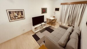 A living room with a flat-screen TV, a sofa, a coffee table, and a dining area with a table and chairs. - Apartamento Alameda Jaú, Jardins, SP (Jardim Paulista São Paulo)