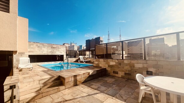 A rooftop pool area with a view of the city skyline, including a tall communication tower. - Apartamento Alameda Jaú, Jardins, SP (Jardim Paulista São Paulo)