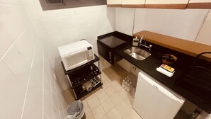 A compact kitchen with a microwave, stove, sink, and a small refrigerator. - Apartamento Alameda Jaú, Jardins, SP (Jardim Paulista São Paulo)