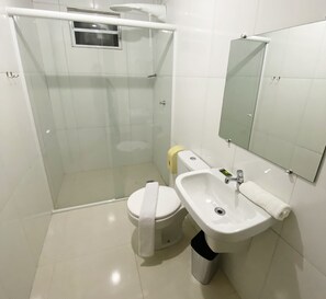 A modern bathroom with a glass-enclosed shower, a toilet, a sink, and a mirror. - Itaipu Hotel Foz do Iguaçu (Foz do Iguaçu)