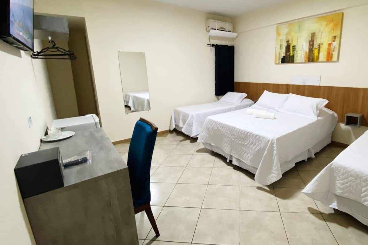 A hotel room with two single beds, a desk with a chair, a TV, and a painting on the wall.