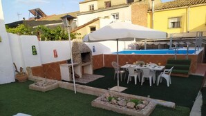 A backyard with a barbecue grill, a pool, and a dining area with chairs and tables.