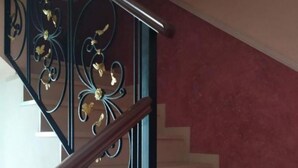 A staircase with ornate black metal railings and a wooden handrail.