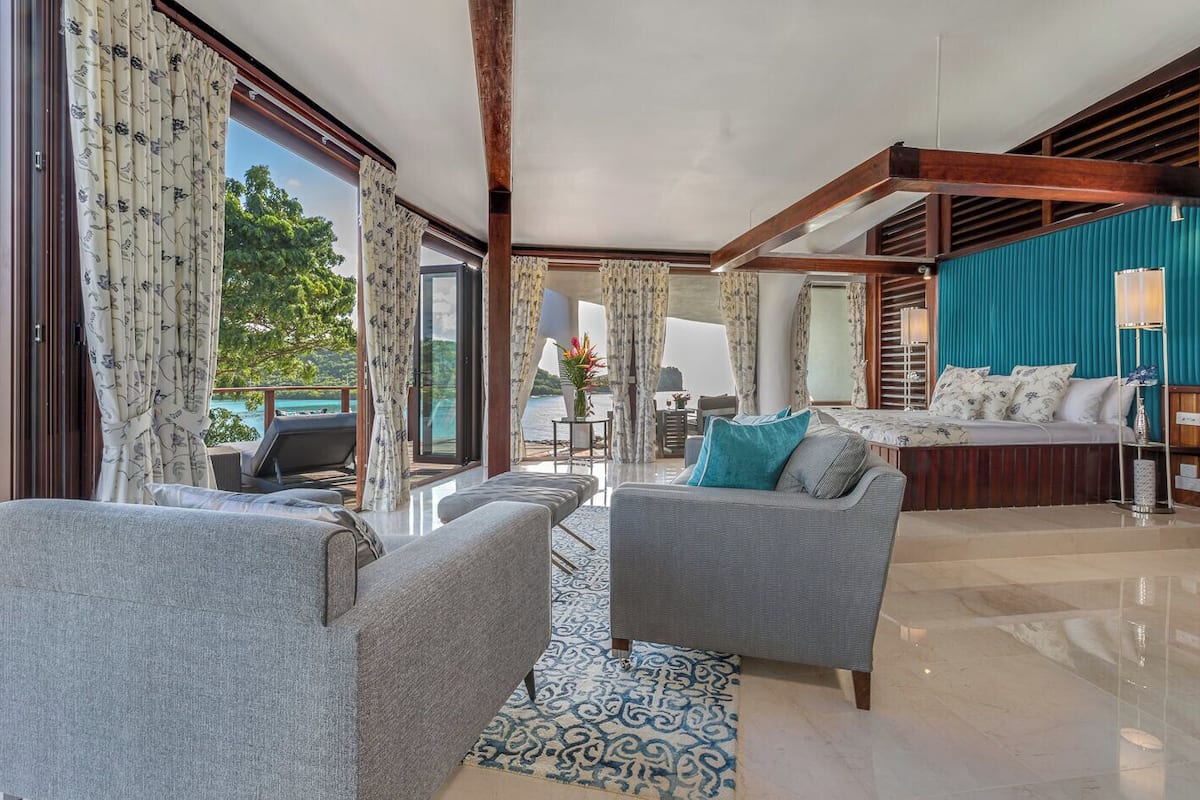 A modern living room with a sofa, a coffee table, and a view of a pool.