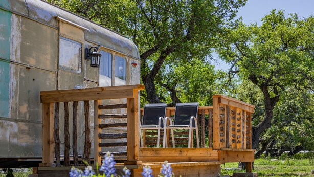 Una caravana antigua con terraza de madera y asientos exteriores.