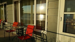 A row of red chairs and a small round table outside a building with large windows. - Snug Harbor Inn - Basic-Water 7 & 10 (Sturgeon Bay)