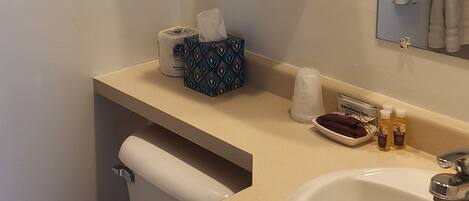 A bathroom with a toilet, sink, and stacked towels.