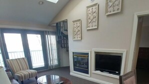 A living room with a sofa, armchairs, a coffee table, a fireplace, and artwork on the walls. - Snug Harbor Inn - Suite 202 & 203 (Sturgeon Bay)