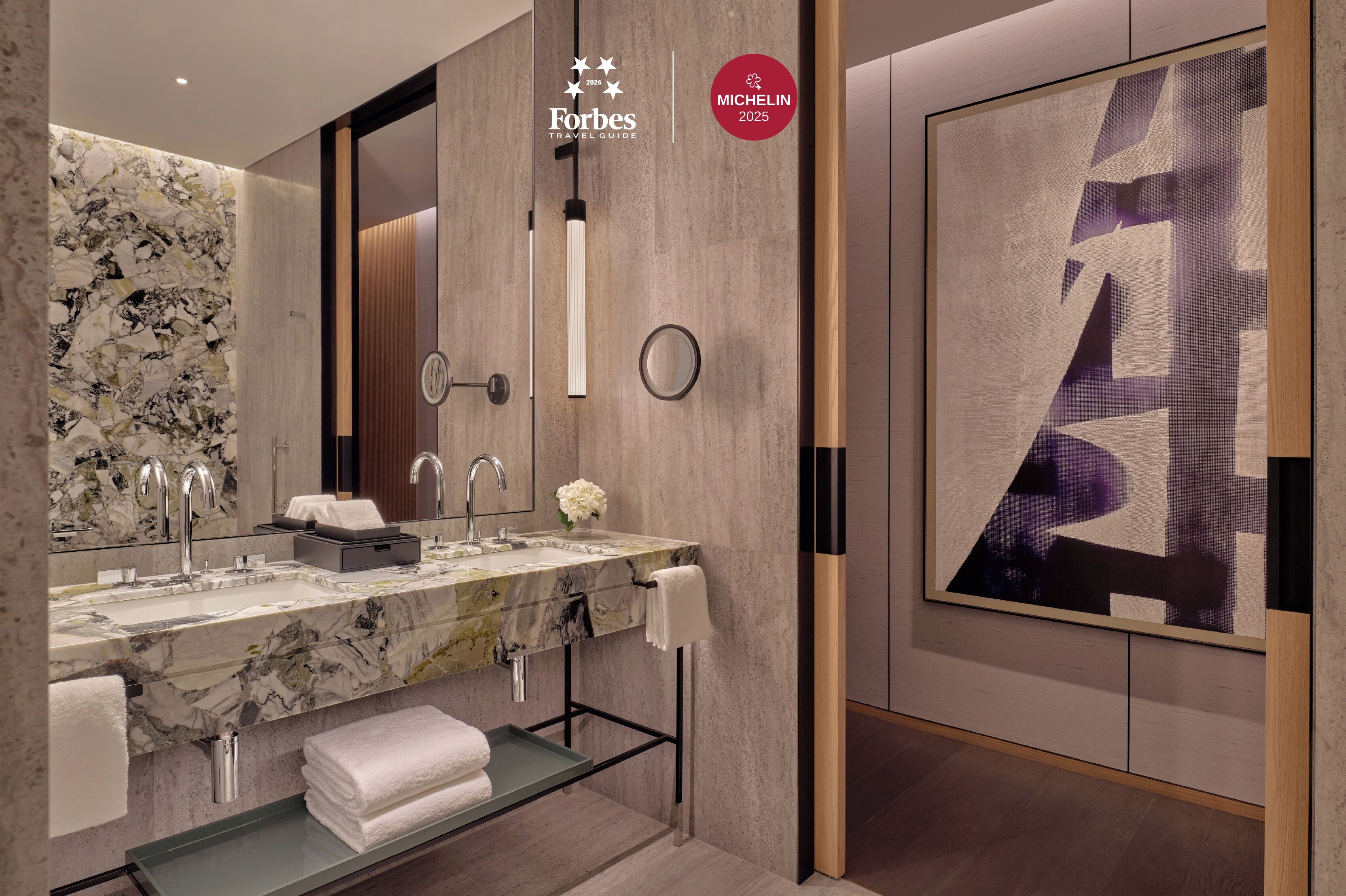 A modern bathroom with a marble sink, two faucets, a large mirror, and a towel rack.