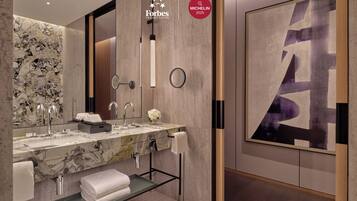 A modern bathroom with a marble sink, two faucets, a large mirror, and a towel rack.