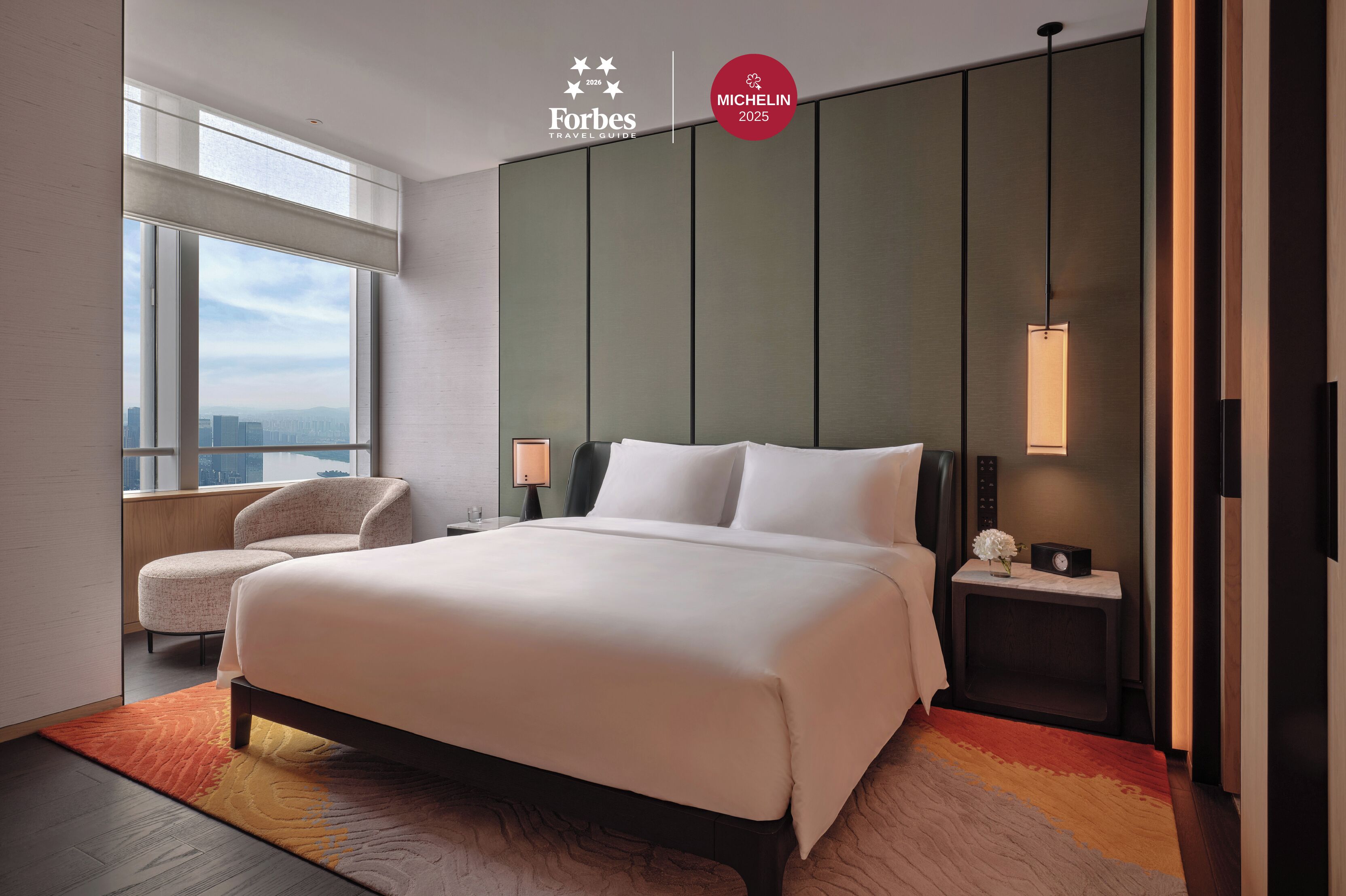 Une chambre d’hôtel moderne dotée d’un grand lit, d’un coin salon, d’une table de chevet et offrant une vue sur la ville.