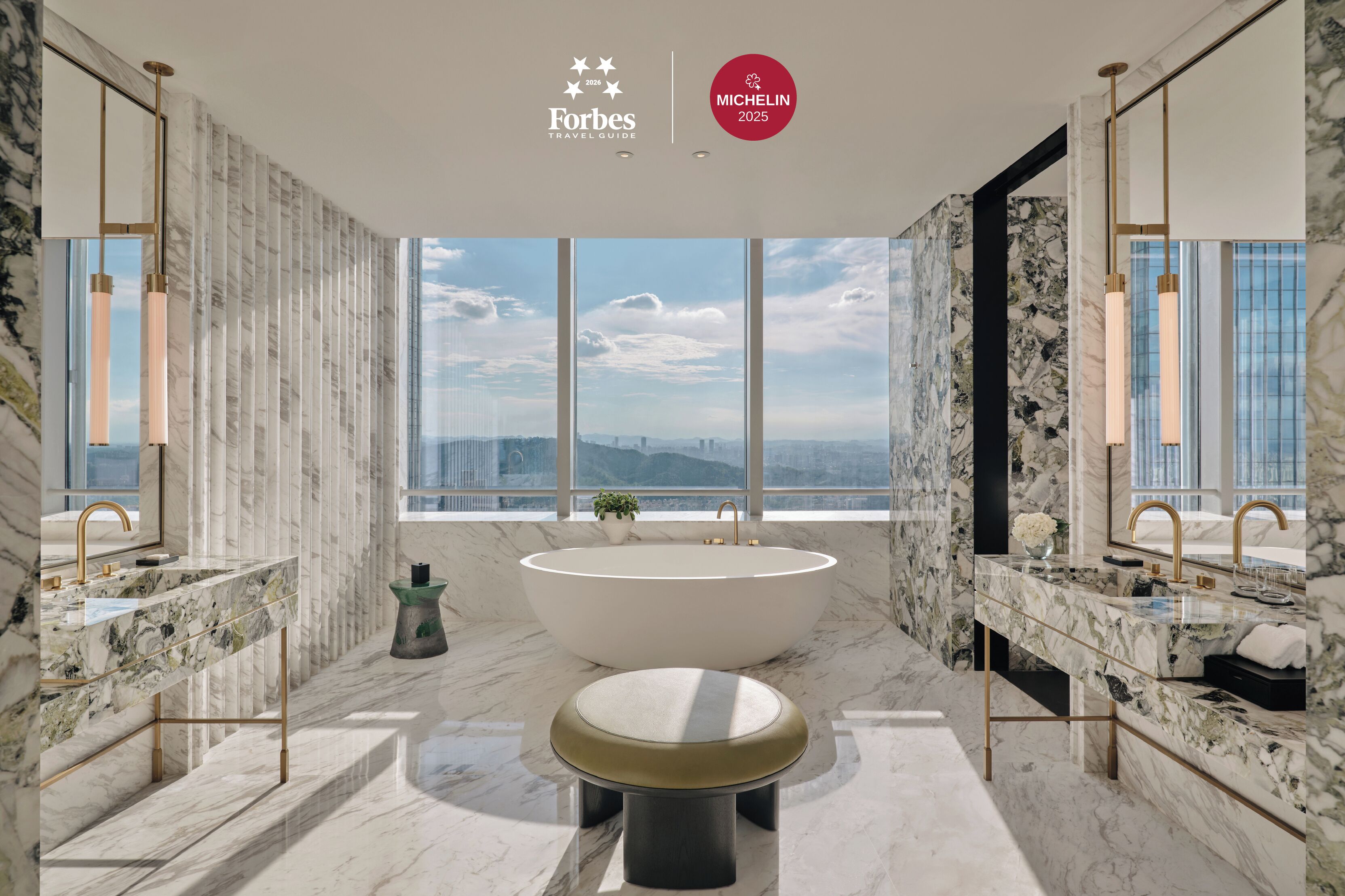 Un bagno moderno con una vasca freestanding, due lavabi e un'ampia finestra con vista sulla città.