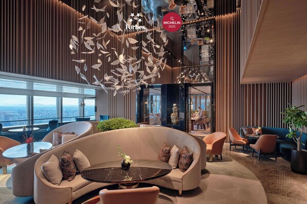 A modern hotel lobby with a curved sofa, a round table, and a city view through large windows. - Park Hyatt Changsha (Changsha)