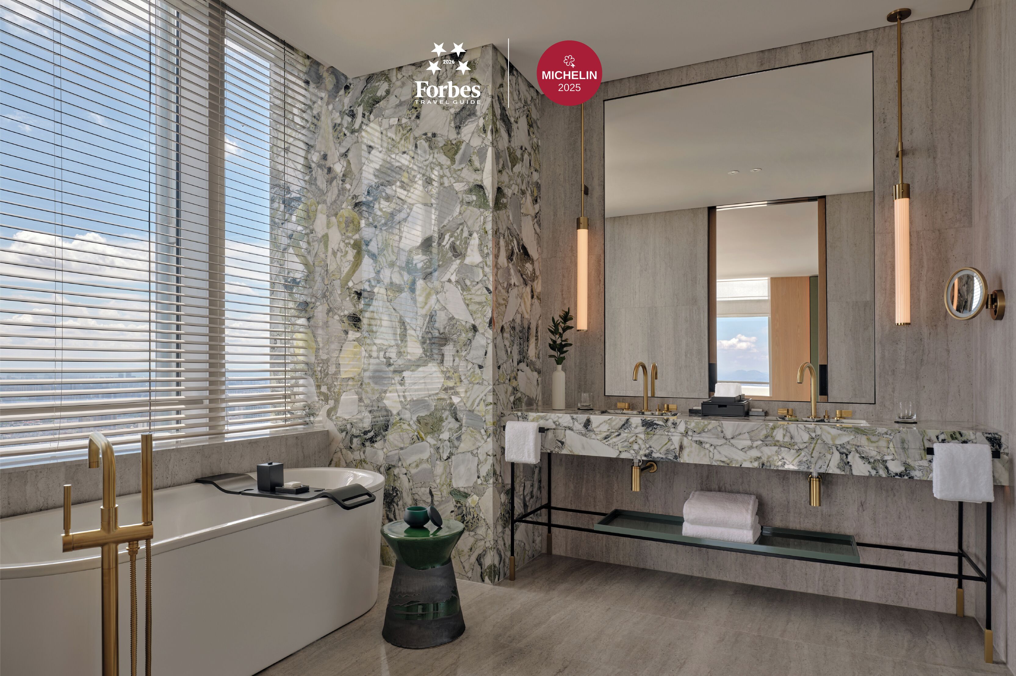 A modern bathroom with a marble vanity, a large mirror, and a bathtub.
