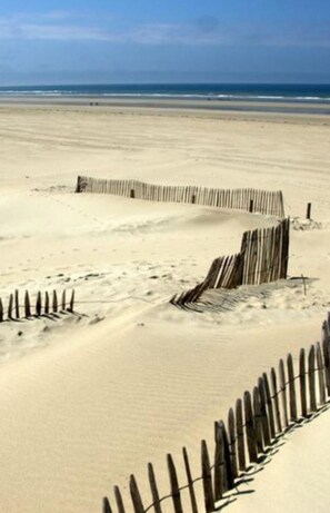 A sandy beach with a wooden fence curving along the shoreline. - Berck sur Mer Appartement à 50m de la Plage! (Berck)