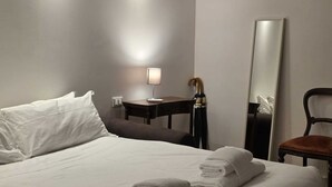 Une chambre d’hôtel avec un grand lit, un bureau, une chaise et un miroir.