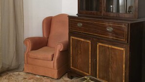 Une pièce d’angle avec un meuble en bois, une chaise en osier et un rideau.