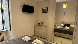 Een moderne slaapkamer met een groot bed, een dressoir, een televisie en een spiegel.