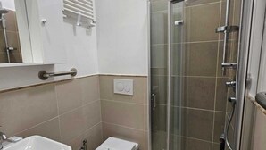 Moderni kylpyhuone, jossa on lasiseinällä varustettu suihku, wc ja pesuallas.