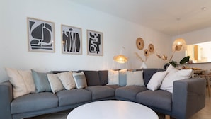 A modern living room with a grey sectional sofa, a round white coffee table, and decorative wall art. - Vivenda Duneta - in Walking Distance to the Beach by Lisbeyond (Aljezur)