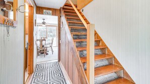 Una scala di legno con un tappeto decorato che conduce a una stanza con una ventola a soffitto e un cartello con la scritta 'Welcome'.