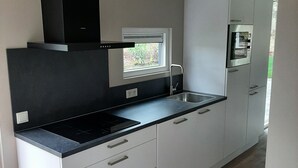 Une cuisine moderne avec des armoires blanches, un plan de travail noir et un four encastré.