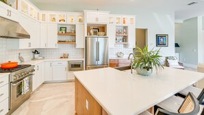 Una cucina moderna con mobili bianchi, elettrodomestici in acciaio inossidabile e un'isola centrale.