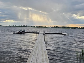A wooden pier extending into a body of water with a small boat docked at the end. - 6 Mile Lodge (Devils Lake)