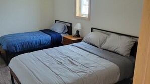 Une chambre avec deux lits, une table de chevet, une fenêtre et un luminaire au plafond.
