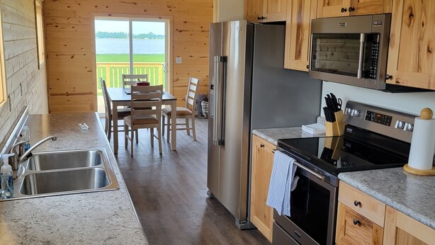 Une cuisine dotée de meubles en bois, d’appareils électroménagers en acier inoxydable, d’un plan de travail en granit et offrant une vue sur un lac.