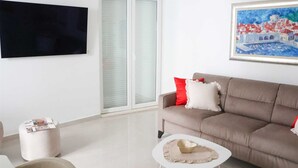 Uma sala de estar com sofá, mesa de centro, televisão e um quadro na parede.