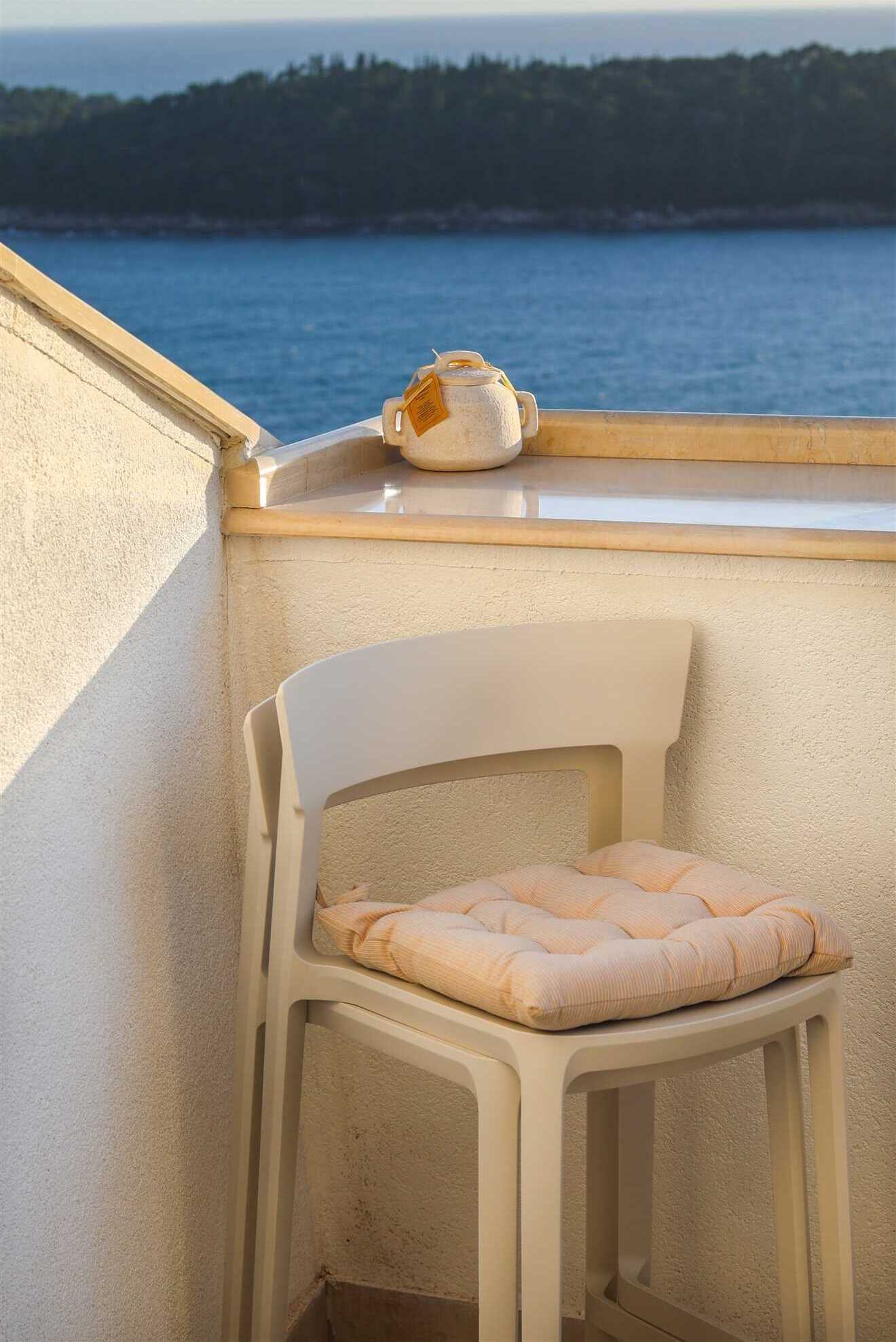 Una silla con cojín en un balcón con vista al agua.