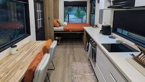 A compact, modern room with a bed, a dining area, and a kitchenette. - Blue Lakes Village (Upper Lake)