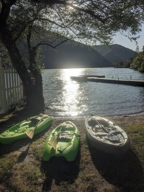 Escena junto al lago con kayaks y un muelle.