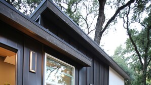 A modern house with a dark exterior, a small patio with a fire pit, and a neatly trimmed lawn. - Blue Lakes Village (Upper Lake)