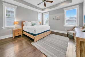 Cozy retreat with a comfortable bed, desk, and nightstand, plus a large window and ceiling fan.