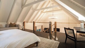 Een slaapkamer met een groot bed, een houten bureau en uitzicht op de zolder door een raam.