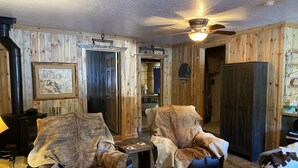 A cozy room with two leather armchairs, a ceiling fan, and a rustic wooden wall. - Bunkhouse at Coal Creek Mountain Lodge (Darby)