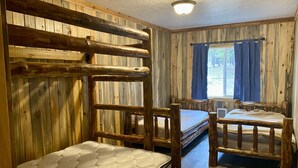 A rustic cabin-style room with two bunk beds and a small table. - Bunkhouse at Coal Creek Mountain Lodge (Darby)