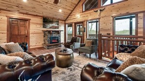 L’intérieur d’une cabane en rondins, avec une cheminée, des canapés en cuir et une cheminée en pierre.