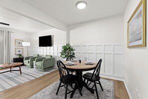 Ein moderner Essbereich mit einem runden Tisch, schwarzen Stühlen und einem grünen Sofa.