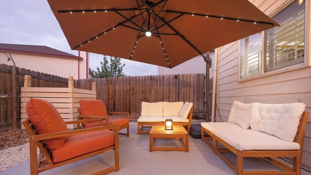 Eine Terrasse im Freien mit Holzmöbeln, darunter eine Couch, Stühle und ein Tisch.