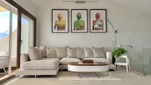 Un soggiorno moderno con un divano angolare beige, un tavolino rotondo e tre opere d'arte incorniciate appese al muro.