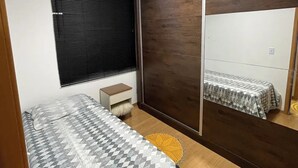 Une chambre à coucher comprenant un lit, une table de chevet, un miroir et une armoire.