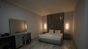 Een moderne slaapkamer met een bed, nachtkastjes, een bureau en een stoel.