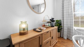 A wooden console table with a mirror, a candle, and a tray with cups and a coffee maker. - Lakeside 1bd Condo with King bed Close to it all! (Branson)