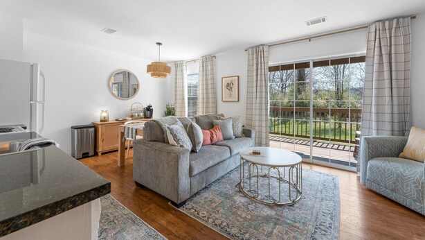 A modern living room with a grey sofa, a round coffee table, and a large window with curtains. - Lakeside 1bd Condo with King bed Close to it all! (Branson)