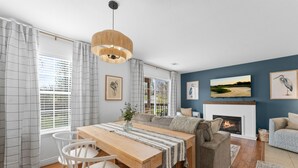 A modern living room with a fireplace, a dining area with a wooden table and chairs, and a sofa. - Lakeside 1bd Condo with King bed Close to it all! (Branson)