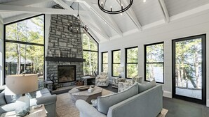 Un salón espacioso con chimenea de piedra, ventanas amplias y muebles modernos.